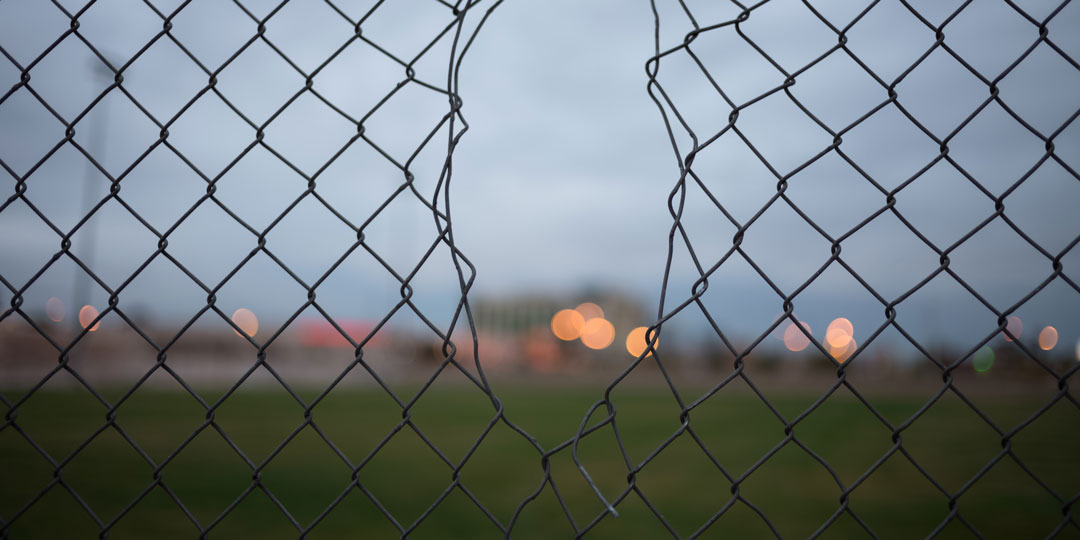 Fence broken or cut open blurry background with buildings and lights